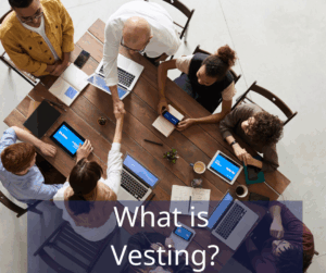group of people with computers at a table working together. Text overlay: What is vesting?