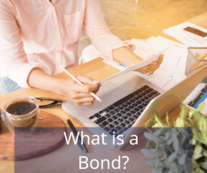 woman at desk reviewing papers in front of a laptop. Text overlay: What is a Bond