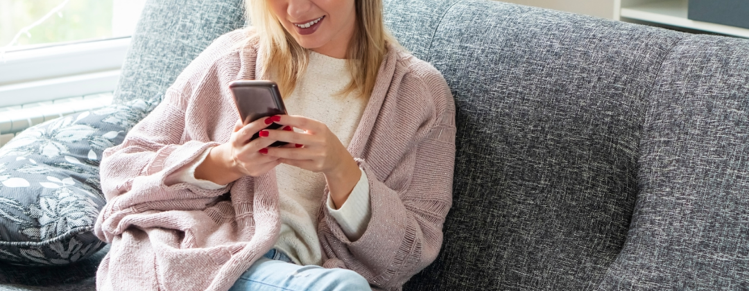 girl on phone sitting on a couch
