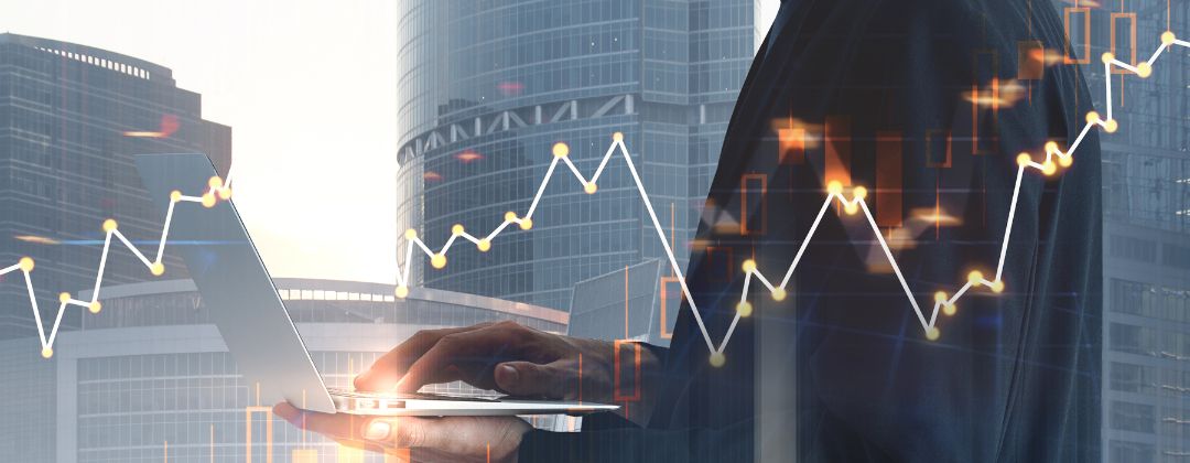 man holding computer with stock market graph overlay.