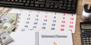 desktop filled with a calendar, money, calculator and keyboard.