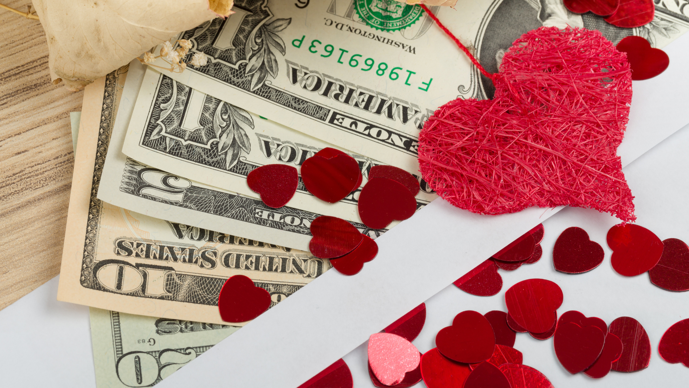 money on a table with valentines hearts.