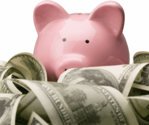 Pink piggy bank hiding in a pile of money.