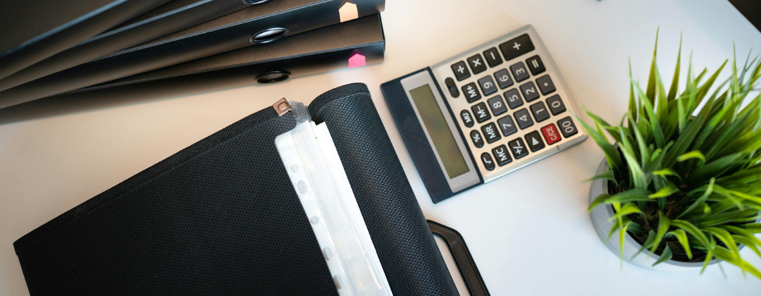 desktop with calculator, plant and files.