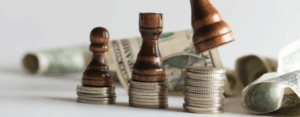 chess pieces on stacked coins with dollar bills in the background